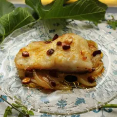 Filete de bacalao dorado sobre cebolla caramelizada y pasas. Una de las mejores recetas de bacalao.