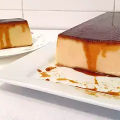 Dos porciones de pudin de pan con caramelo líquido, una en primer plano y otra al fondo.