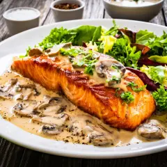 Salmón cremoso con champiñones, una de las mejores recetas con salmón, acompañado de ensalada fresca.