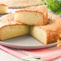 Bizcocho sin huevo esponjoso y dorado, servido en un plato gris con un cuchillo de plata. Perfecto para un postre ligero.