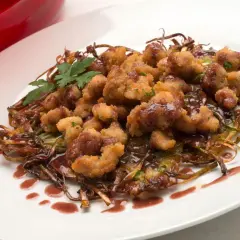 Mollejas de cordero rebozadas y crujientes, servidas sobre verduras salteadas y bañadas en una salsa oscura. ¡Una delicia para aprender como hacer mollejas de cordero!