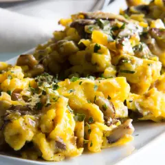 Delicioso revuelto de champiñones con perejil picado, servido en un plato blanco.