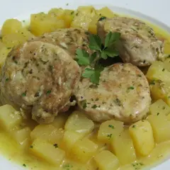 Cuatro medallones de solomillo al ajillo, jugosos y dorados, servidos con patatas cortadas en cubos y perejil picado.