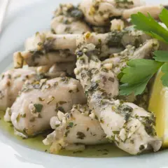 Deliciosas ancas de rana en salsa de ajo y perejil, servidas con gajos de limón. Una receta clásica para disfrutar.