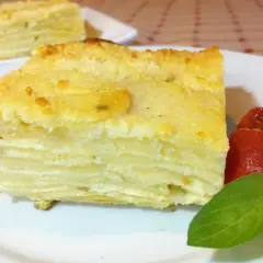 Delicioso pastel de papa en capas, un milhojas de patata gratinado, servido con tomates y albahaca.