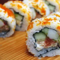 Rollos de sushi caseros con salmón, aguacate y pepino, cubiertos de tobiko. ¡Una guía fácil de como hacer sushi en casa!