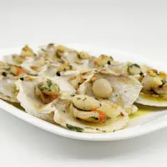 Zamburiñas a la plancha, jugosas y doradas, servidas en su concha con perejil picado y un toque de ajo.