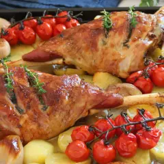 Pierna de cordero al horno jugosa, con patatas, tomates cherry y cebolla. ¡Un festín para los sentidos!