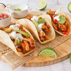 Cuatro deliciosos tacos de pollo con aguacate, cilantro y crema, acompañados de pico de gallo y limón.