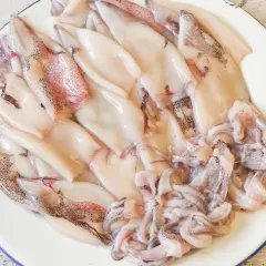 Plato con chipirones limpios y tentáculos listos para freír. Se aprecian sus manchas oscuras y tonos rosados.