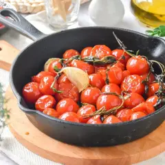 Tomates cherry confitados en sartén de hierro fundido con ajo y hierbas. Un plato delicioso y aromático.