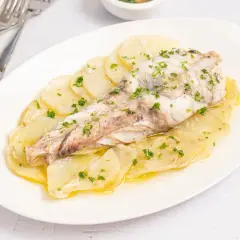 Delicioso rape al horno sobre cama de patatas laminadas, espolvoreado con perejil fresco.
