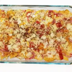 Nachos con queso horneados, cubiertos con trozos de tocino y pimientos rojos.