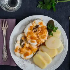 Merluza a la gallega servida con patatas cocidas y perejil. Un plato tradicional gallego.