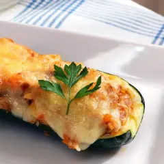Calabacines rellenos de atún, gratinados con queso y decorados con perejil. Un plato delicioso y saludable.