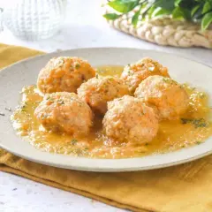 Sabrosas albóndigas de pollo en salsa, servidas en un plato con perejil picado. Un plato casero y reconfortante.