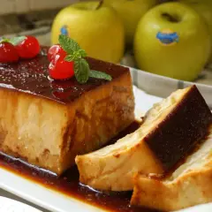 Delicioso pudin de manzana con caramelo, decorado con cerezas y menta. Manzanas verdes al fondo.