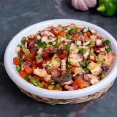 Un refrescante salpicón de pulpo con pimientos, cebolla y perejil, listo para disfrutar.