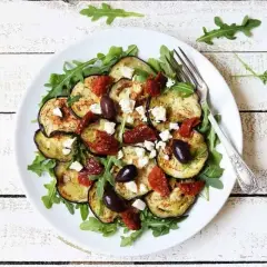Deliciosa ensalada de berenjena asada con rúcula, tomates secos, aceitunas negras y queso feta.