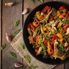 Wok de pollo con pimientos de colores y judías verdes, espolvoreado con sésamo y cebolleta.