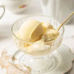 Copa de cristal con cremoso helado de mantecado, lista para disfrutar. Una cuchara dorada toma una porción.
