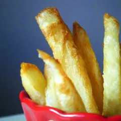 Patatas fritas doradas y crujientes en un recipiente rojo.