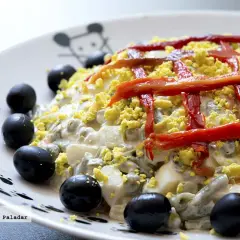 Ensaladilla rusa Thermomix cremosa, decorada con pimientos rojos y aceitunas negras. ¡Perfecta para cualquier ocasión!