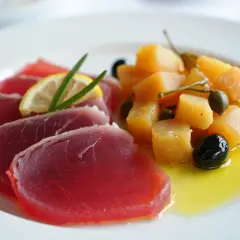 Deliciosa ventresca de atún cruda, servida con patatas, aceitunas y alcaparras en aceite de oliva.