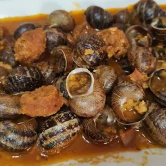 Un plato abundante de caracoles en salsa, con trozos de chorizo y especias, listo para disfrutar.