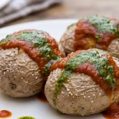 Tres papas arrugadas con mojo rojo y verde, sal marina y puntos de salsa en un plato blanco.
