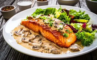 Salmón cremoso con champiñones, una de las mejores recetas con salmón, acompañado de ensalada fresca.