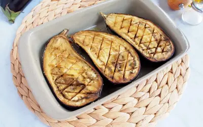 Berenjenas asadas al horno, cortadas por la mitad y con un patrón de rejilla, listas para disfrutar.