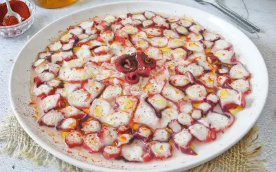 Delicioso carpaccio de pulpo, finas láminas rociadas con aceite de oliva y pimentón, listo para disfrutar.