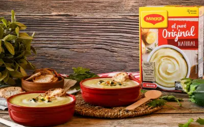 Dos cuencos rojos con cremoso puré de patatas Maggi, tostadas y hierbas. Caja de puré de patatas al lado.
