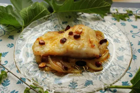 Filete de bacalao dorado sobre cebolla caramelizada y pasas. Una de las mejores recetas de bacalao.