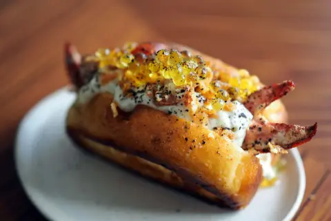 Un delicioso lobster roll receta, con carne de cangrejo, caviar y salsa cremosa en un pan tostado.