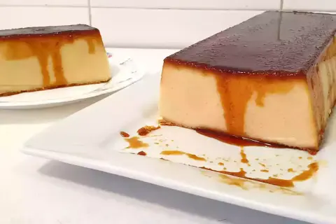 Dos porciones de pudin de pan con caramelo líquido, una en primer plano y otra al fondo.