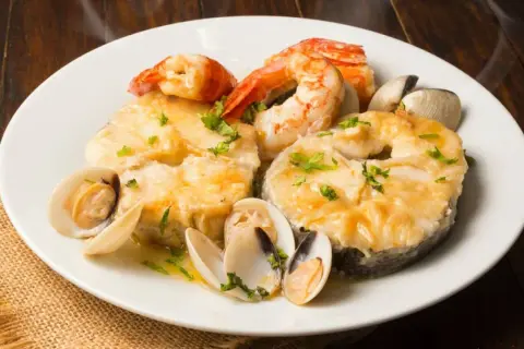 Merluza a la marinera con gambas y almejas, un plato delicioso y aromático.