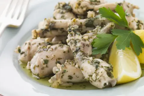 Deliciosas ancas de rana en salsa de ajo y perejil, servidas con gajos de limón. Una receta clásica para disfrutar.