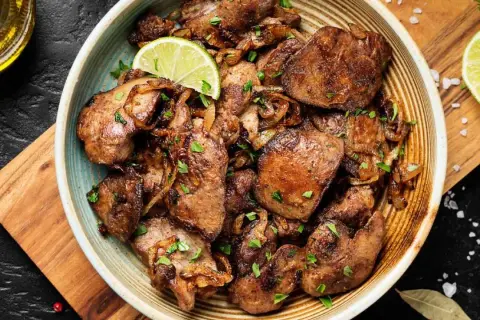 Sabrosos higaditos de pollo encebollados, salpicados de perejil fresco y adornados con rodajas de lima. Un plato casero irresistible.