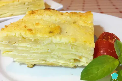 Delicioso pastel de papa en capas, un milhojas de patata gratinado, servido con tomates y albahaca.