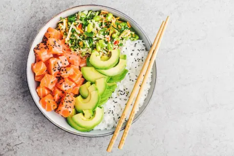 Un delicioso poke de salmón con aguacate, arroz blanco y vegetales frescos.