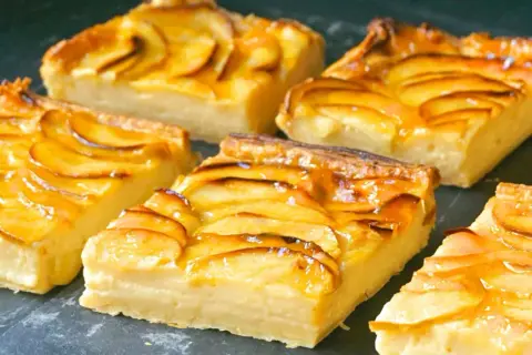 Porciones de tarta de manzana con crema pastelera, cubiertas con un glaseado brillante y rodajas de manzana caramelizadas.