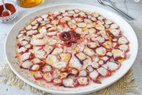 Delicioso carpaccio de pulpo, finas láminas rociadas con aceite de oliva y pimentón, listo para disfrutar.