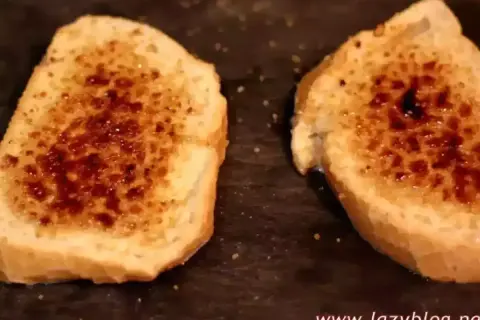 Dos rebanadas de pan tostado con azúcar caramelizada encima, listas para ser horneadas como torrijas.