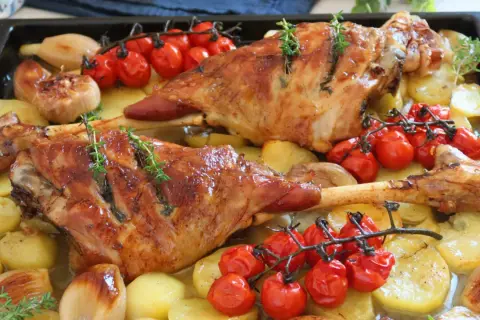 Pierna de cordero al horno jugosa, con patatas, tomates cherry y cebolla. ¡Un festín para los sentidos!
