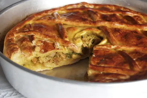 Empanada de carne dorada y crujiente, con un relleno jugoso visible en un corte. Perfecta para compartir.