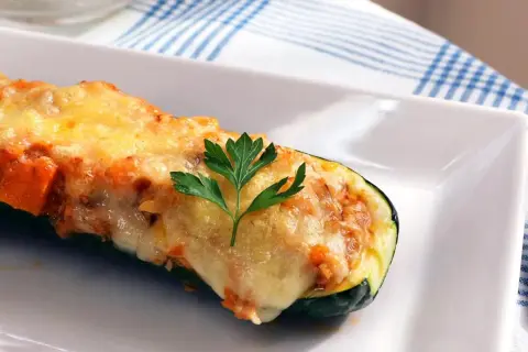 Calabacines rellenos de atún, gratinados con queso y decorados con perejil. Un plato delicioso y saludable.