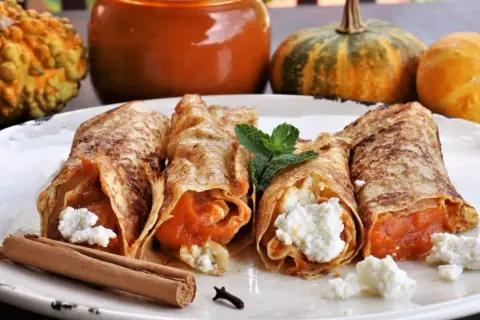 Rollitos de crepes rellenos de calabaza y queso fresco, decorados con menta y canela. Ideales para recetas con calabaza.