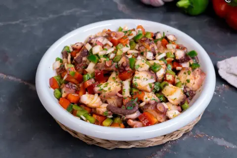 Un refrescante salpicón de pulpo con pimientos, cebolla y perejil, listo para disfrutar.